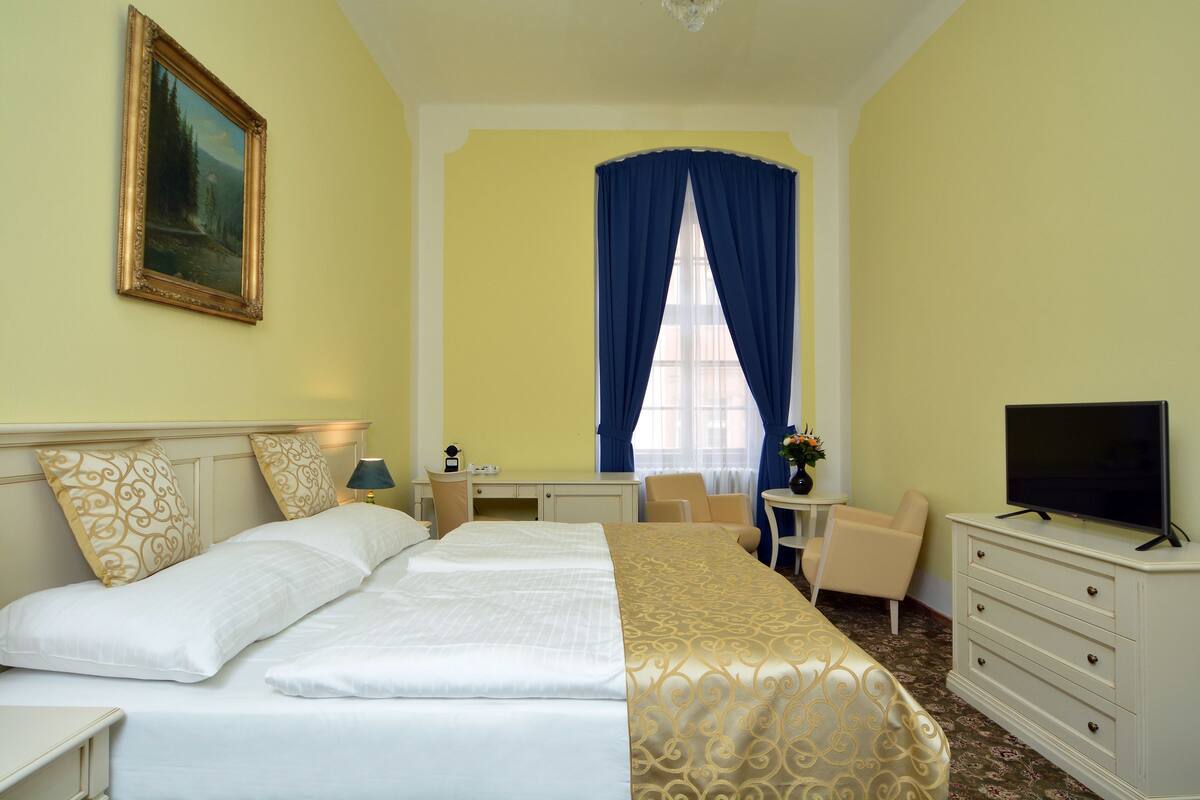 Une chambre d’hôtel avec un grand lit, un bureau, une chaise, une télévision et un tableau au mur.