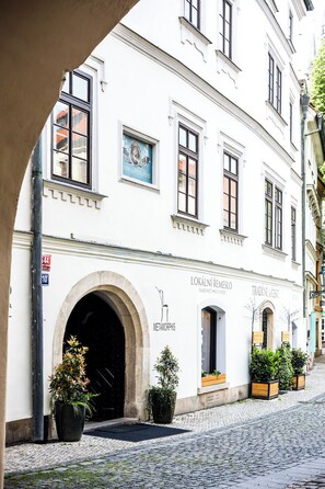 A historic building with an arched entrance, a sign for 'Metamorphis,' and a cobblestone street. - Hotel Metamorphis (Prague)