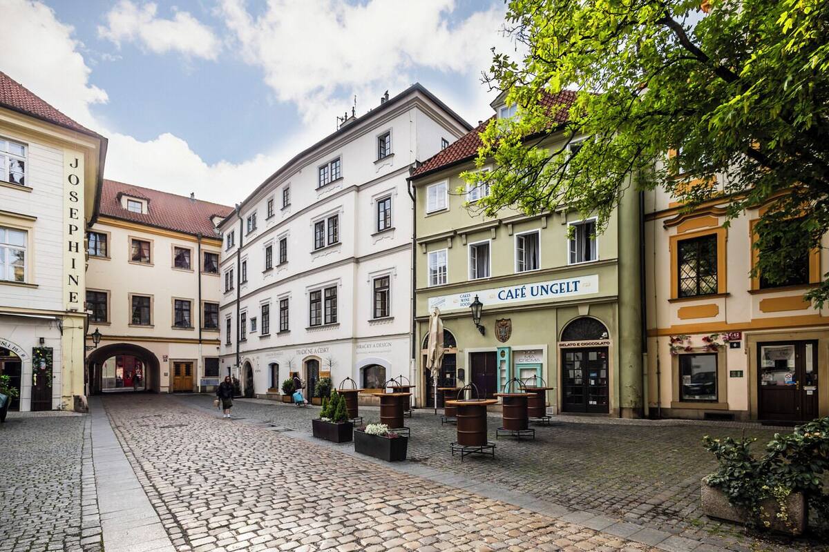 Une place pavée bordée de bâtiments historiques, avec un café et des tables en plein air.