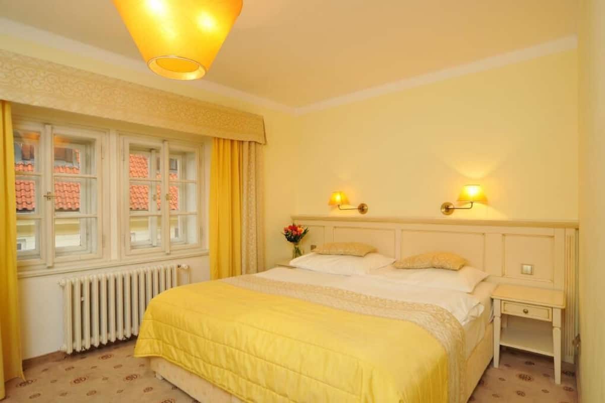 Une chambre d’hôtel avec un lit, des lampes de chevet, une table de nuit et une fenêtre avec des rideaux.