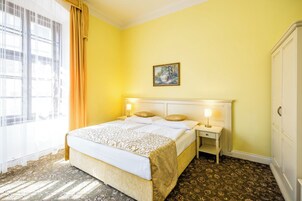 Quarto de hotel com cama, mesas de cabeceira, um armário e um quadro na parede.