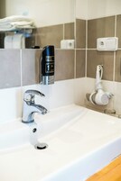 Un lavabo con dispenser per sapone, un rubinetto e uno scaffale per asciugamani sullo sfondo.