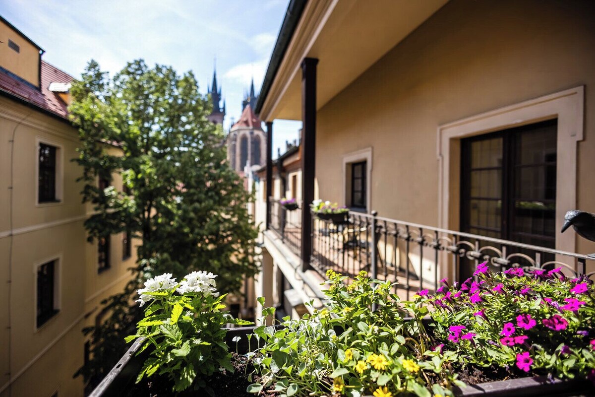 Een balkon met potplanten en uitzicht op een kerktoren.