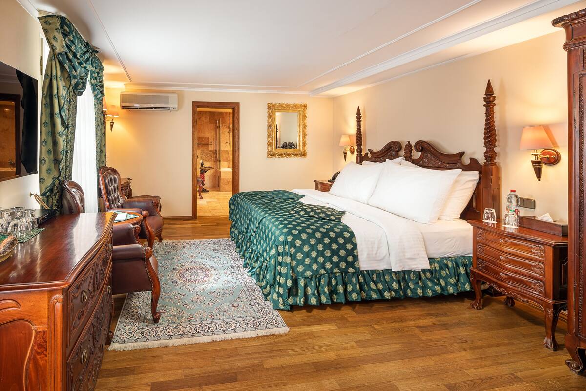 Ein Hotelzimmer mit einem großen Bett, einem Holzkapfen, einem Schreibtisch mit Stühlen und einem Spiegel an der Wand.