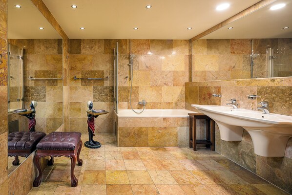 A luxurious bathroom with a large bathtub, a separate shower area, and a vanity with a sink. - Hotel U Prince Prague by BHG (Prague)