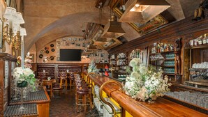 Un bar avec un comptoir en bois, des tabourets et une variété de bouteilles et de verres.