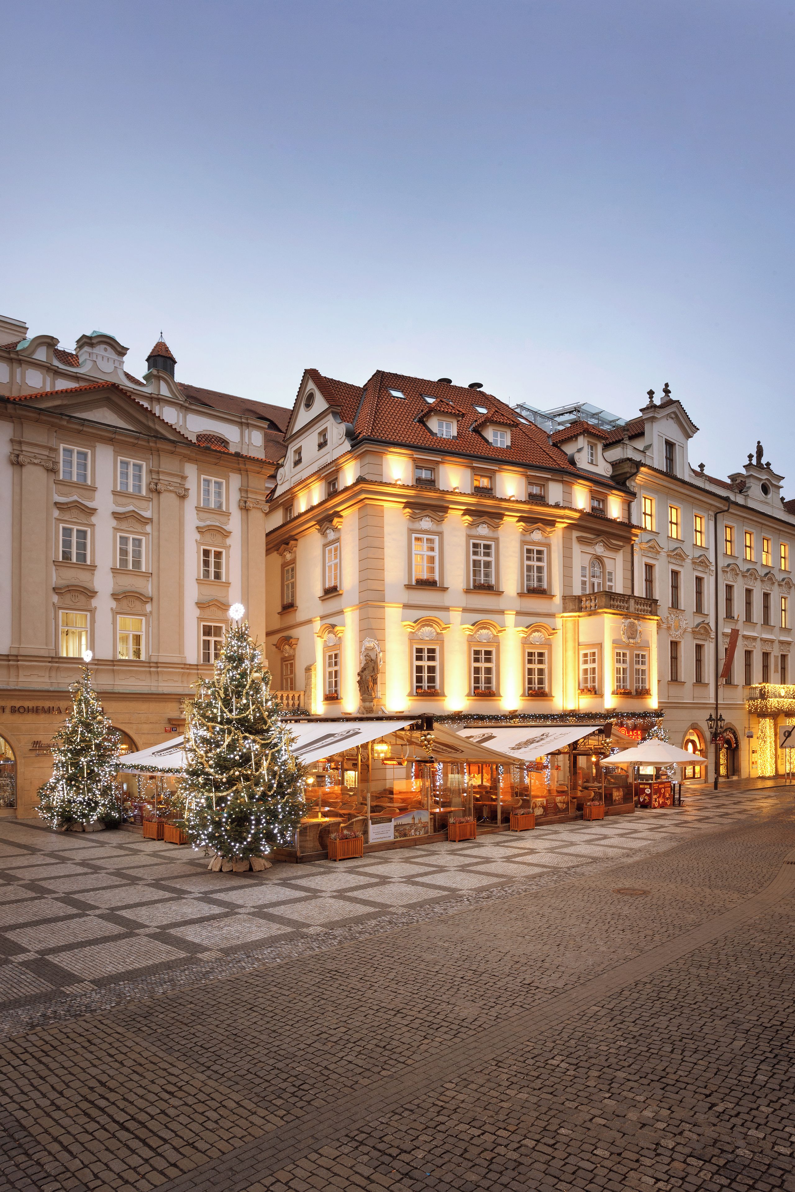 A historic building with a traditional European architectural style, featuring a central courtyard with a Christmas tree and outdoor seating area.