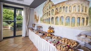 A buffet setup with a variety of food items, a mural of the Colosseum, and a view of greenery through a glass door. - Hotel Roma Prague (Prague)