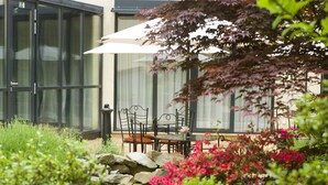 A patio with a table and chairs, surrounded by a garden with various plants and flowers. - Hotel Roma Prague (Prague)