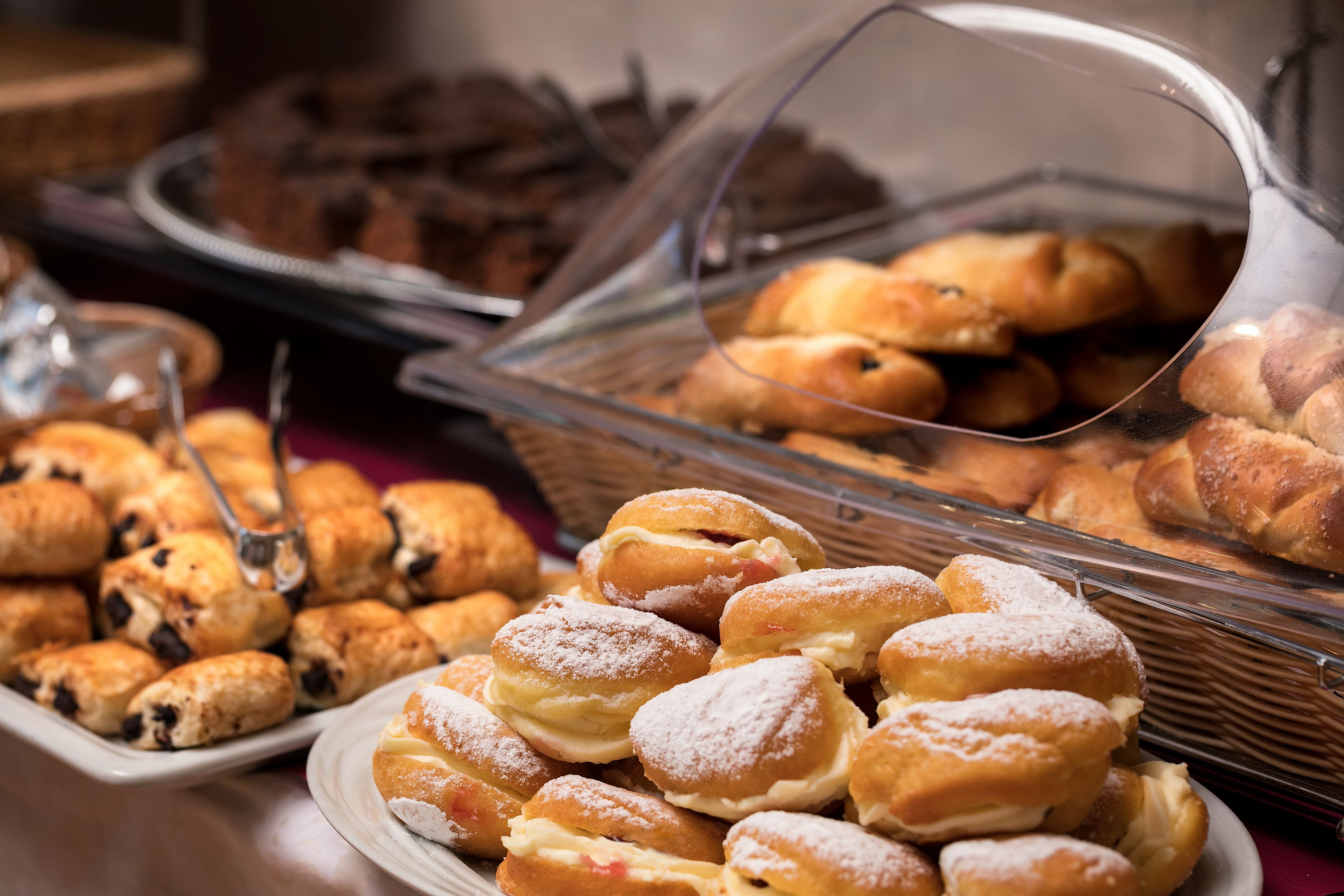 Um buffet com diversos doces e sobremesas, incluindo rolinhos de chocolate e pastéis recheados.