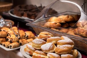 Um buffet com diversos doces e sobremesas, incluindo rolinhos de chocolate e pastéis recheados.