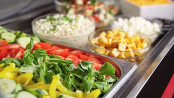 Un bufé con diversas opciones de comida, como ensaladas, frutas y queso.
