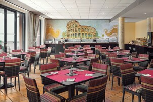 Um restaurante com várias mesas e cadeiras, um mural do Coliseu e uma área de buffet.