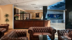 A lobby with leather sofas, a reception desk, a large aquarium, and a potted plant. - Hotel Roma Prague (Prague)