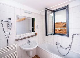 Casa de banho moderna com lavatório, espelho e chuveiro.