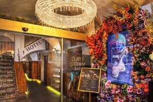 Entrada de hotel com escadaria, um candelabro e decoração floral.