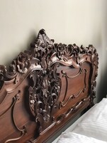 Uma cabeceira de madeira com esculturas detalhadas e design curvo.