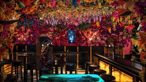 A bar area with a floral wall, multiple stools, and a central table with a blue-lit water feature. - Hotel U Zlatého Stromu Prague by BHG (Prague)