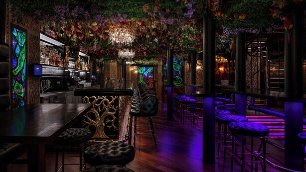 A bar area with a long counter, multiple stools, and a ceiling adorned with hanging plants and a chandelier. - Hotel U Zlatého Stromu Prague by BHG (Prague)
