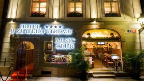 A hotel with a Music Club, featuring a grand entrance, multiple windows with flower boxes, and a well-lit facade. - Hotel U Zlatého Stromu Prague by BHG (Prague)