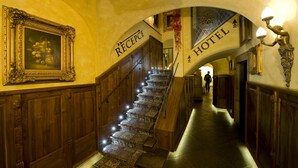 A grand staircase with a wooden handrail and carpeted steps leading to a reception area marked by a sign. - Hotel U Zlatého Stromu Prague by BHG (Prague)