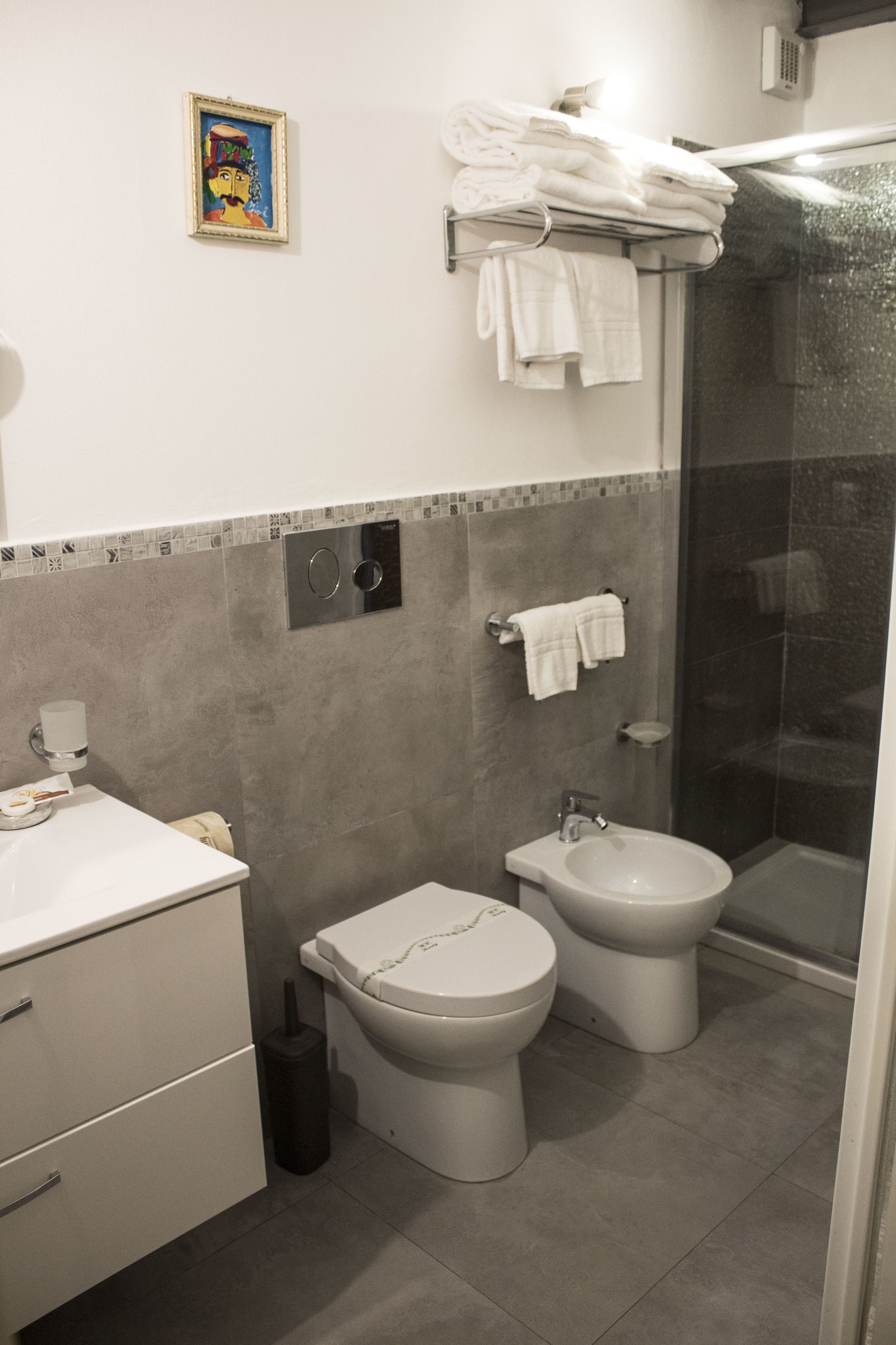 A modern bathroom with a toilet, bidet, and a glass-enclosed shower area.
