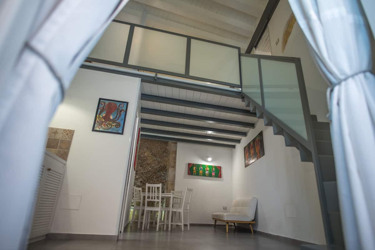 Un amplio salón con una escalera, una mesa de comedor con sillas y obras de arte en las paredes.
