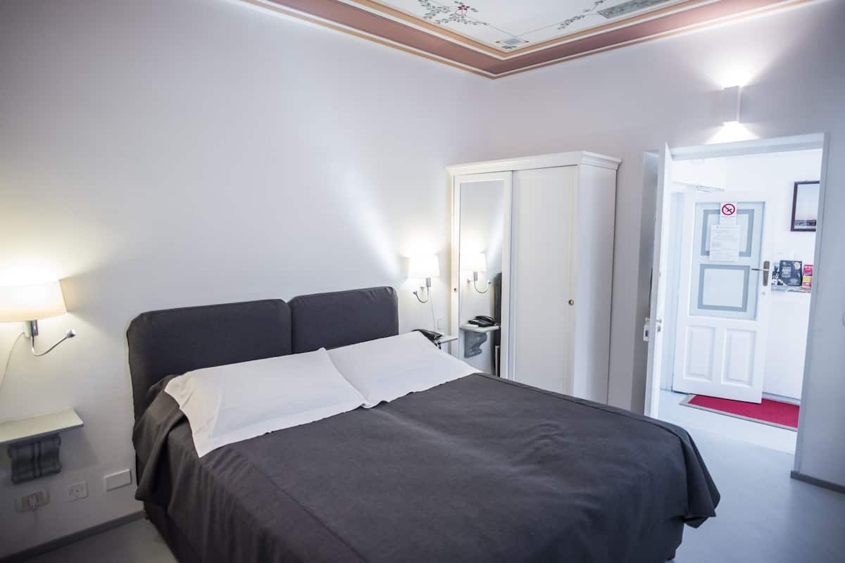 Un dormitorio con cama, armario, mesita de noche y lámpara.