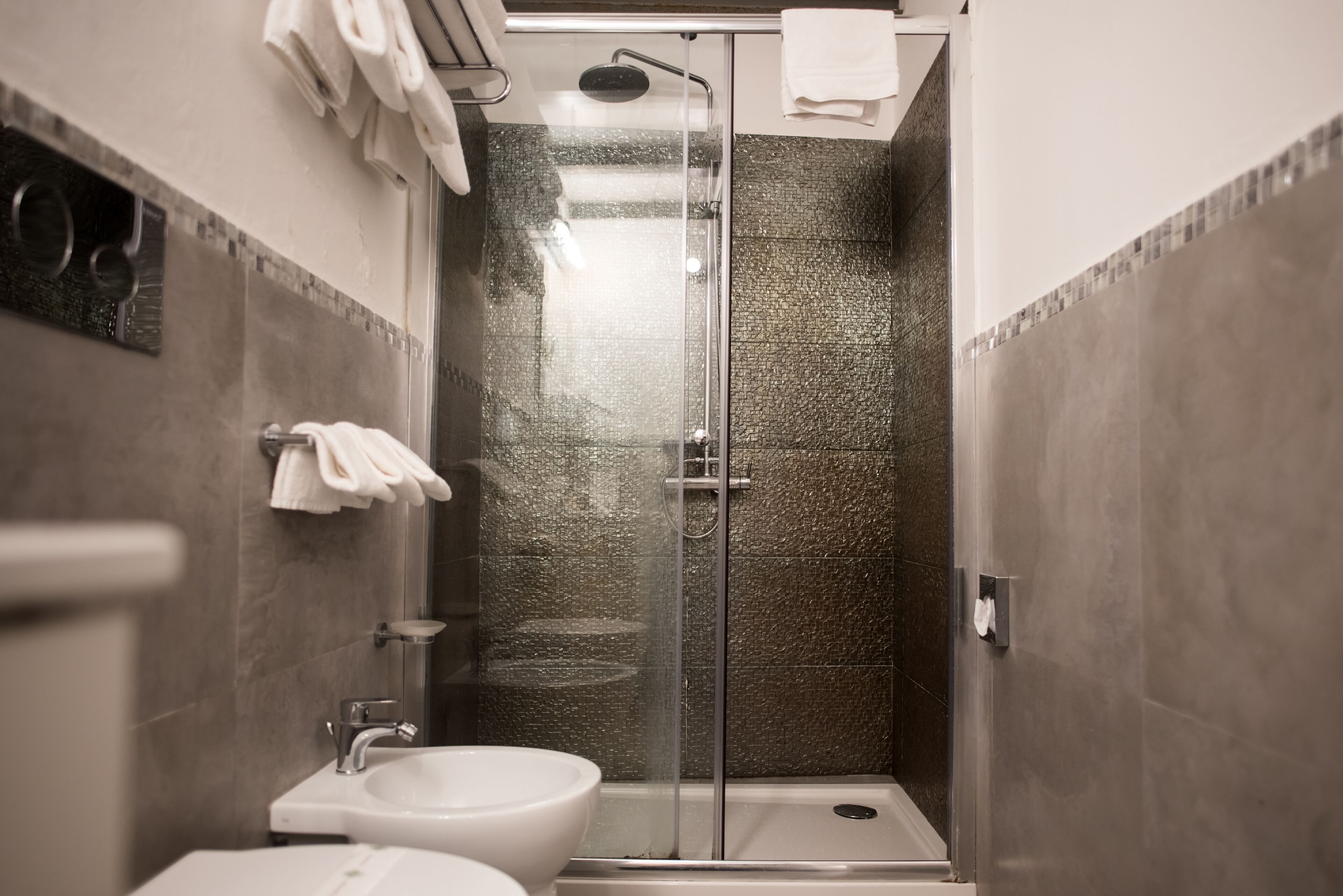 Een moderne badkamer met een douchecabine van glas, een wastafel en een toilet.