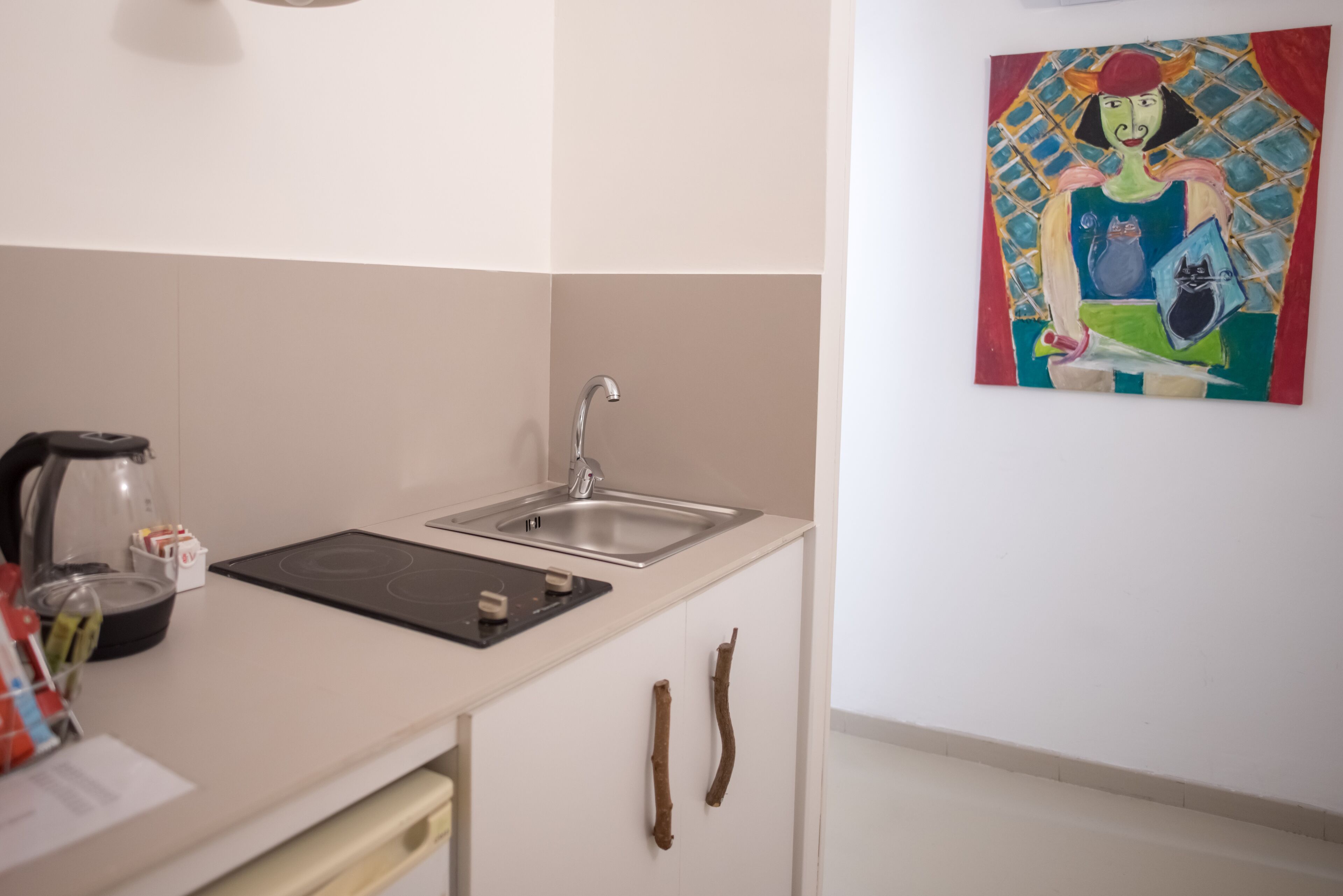 Una cocina con un lavamanos, estufa y un cuadro en la pared.