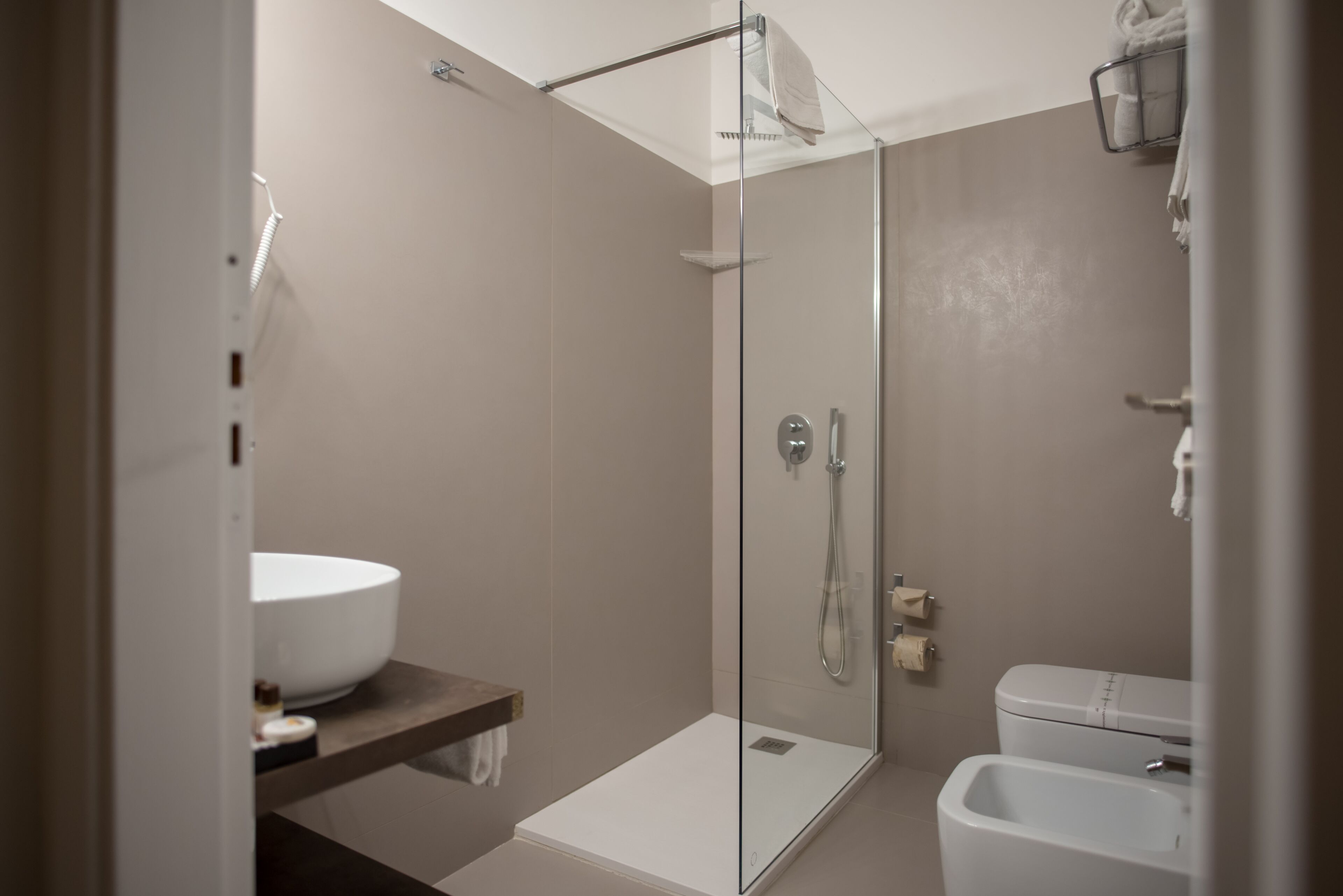 Un bany modern amb dutxa envidriada, un lavabo blanc i un vàter.