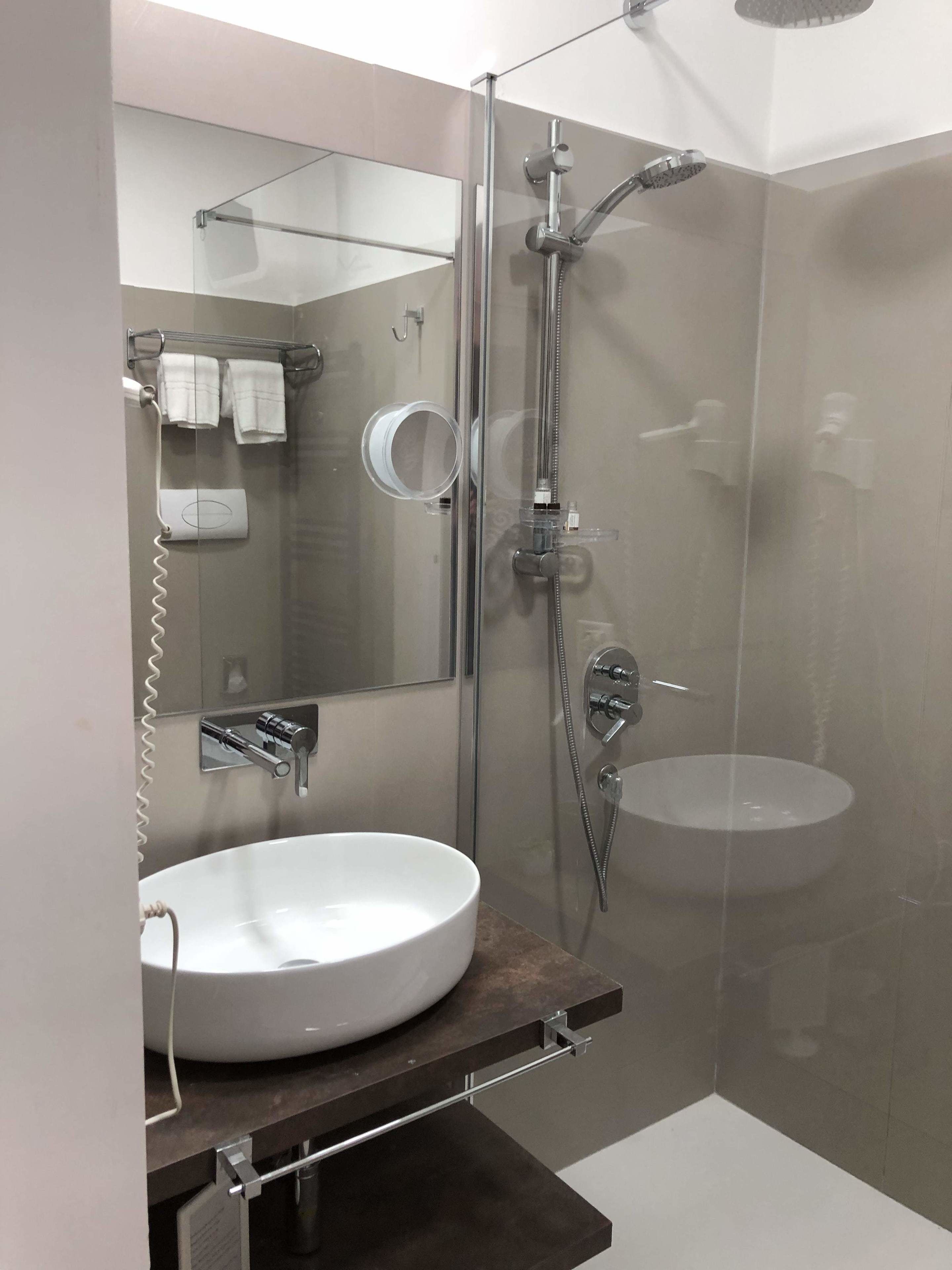 Un baño moderno con ducha de vidrio, lavabo blanco y espejo.