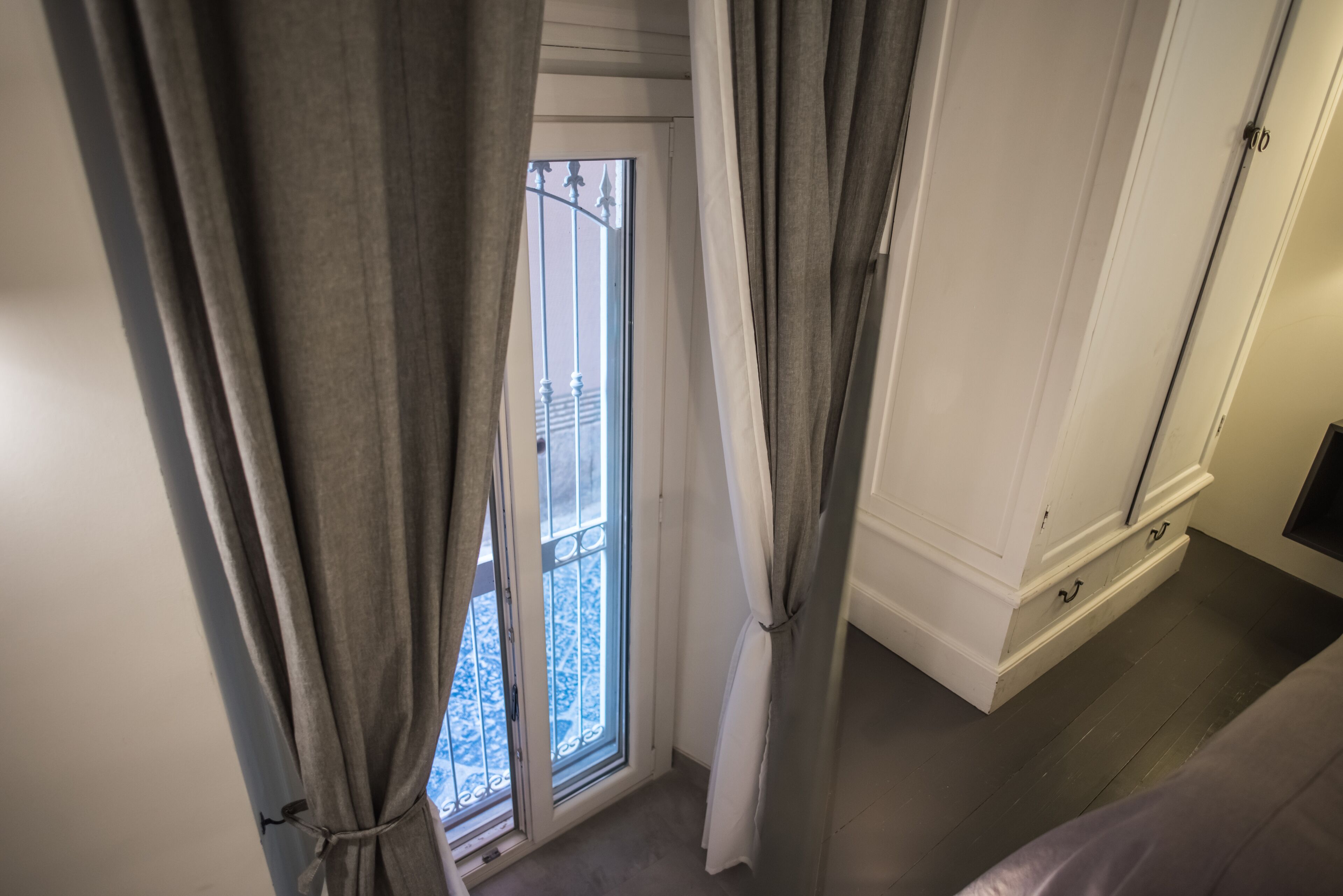 A room with a view of a balcony, a white door, and a wooden floor.