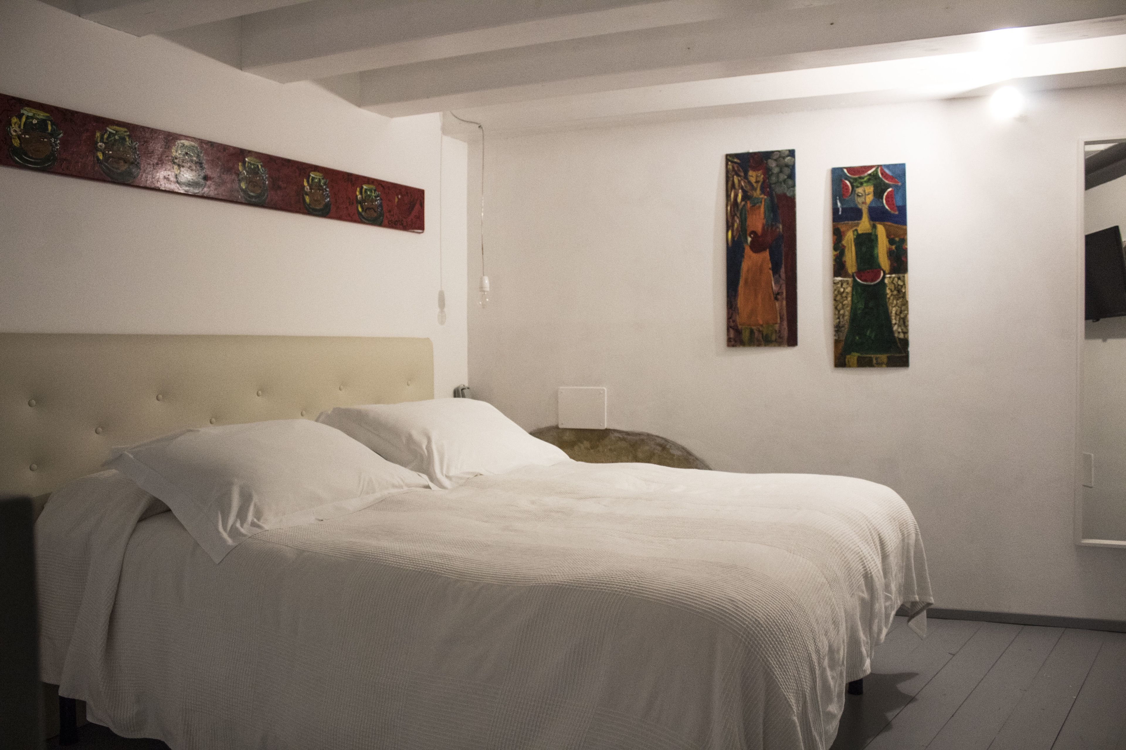 Un dormitorio con una cama grande, un cabecero y dos cuadros en la pared.