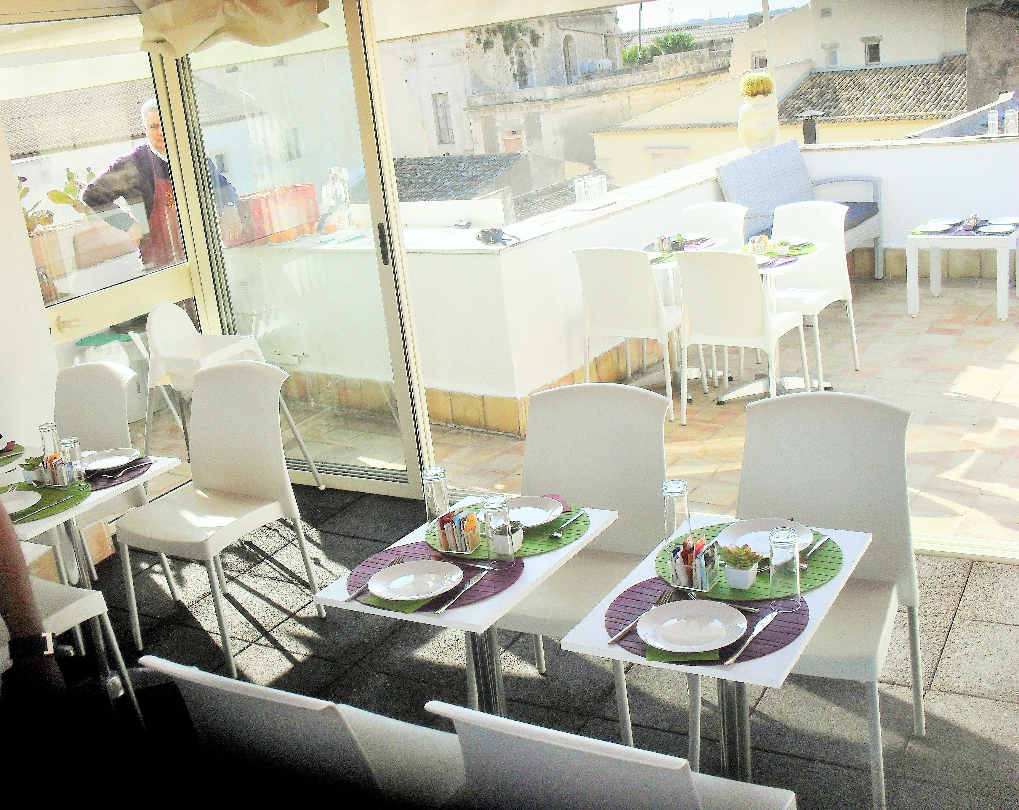 An outdoor dining area with white tables and chairs, arranged for guests.