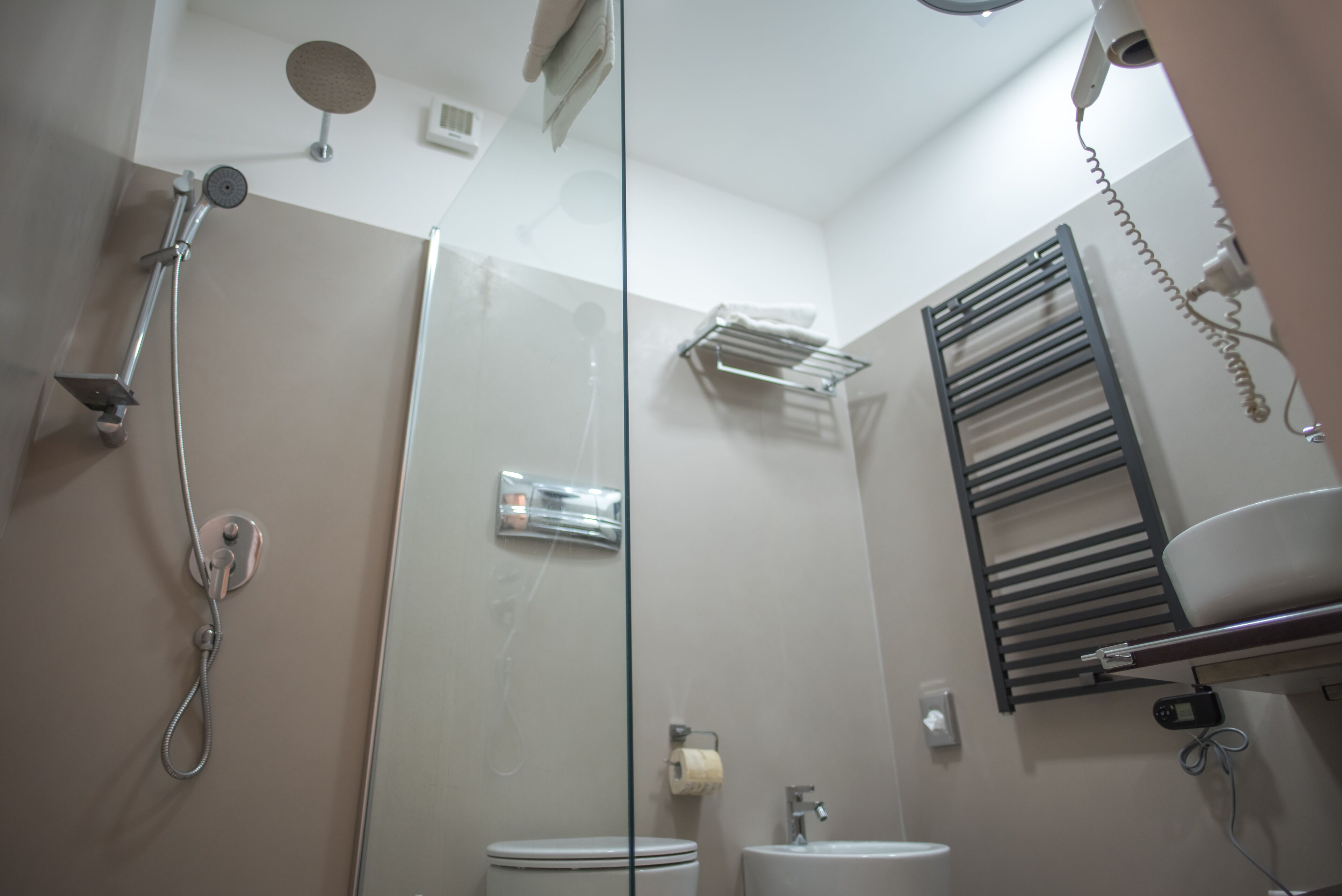 Ein modernes Badezimmer mit Duschkabine aus Glas, Toilette, Waschbecken und Handtuchhalter.