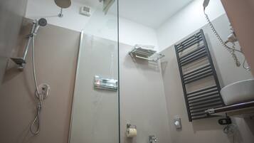 Ein modernes Badezimmer mit Duschkabine aus Glas, Toilette, Waschbecken und Handtuchhalter.