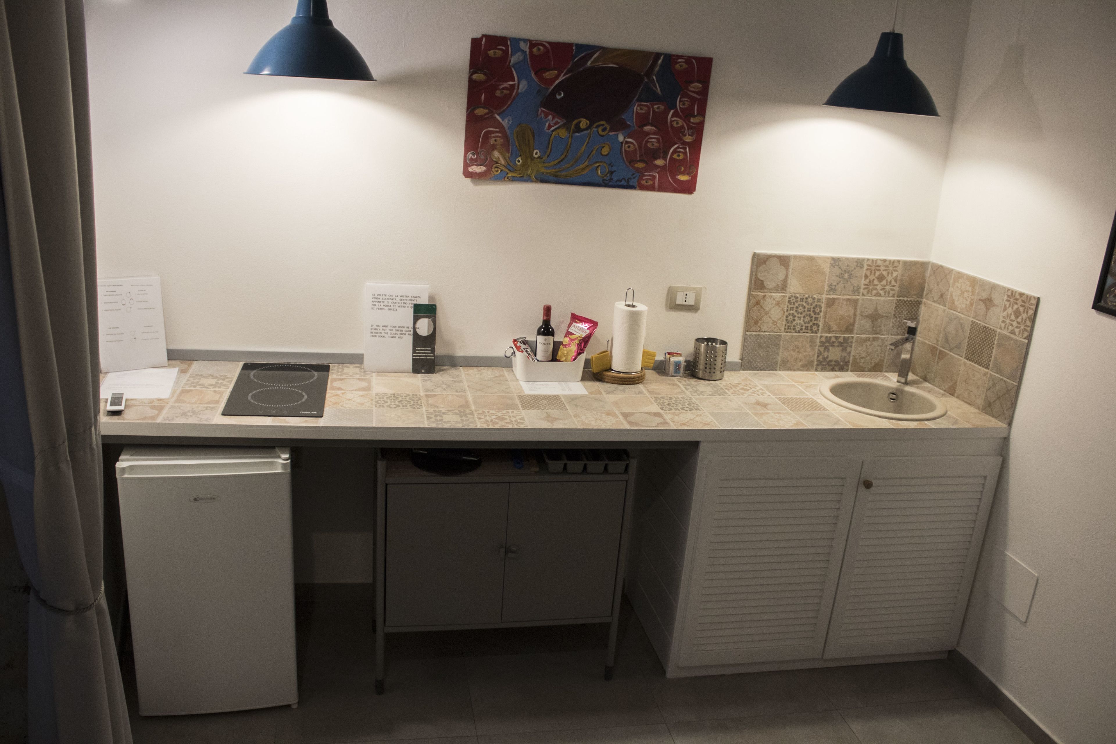 A compact kitchen with a refrigerator, sink, and a countertop with various items.