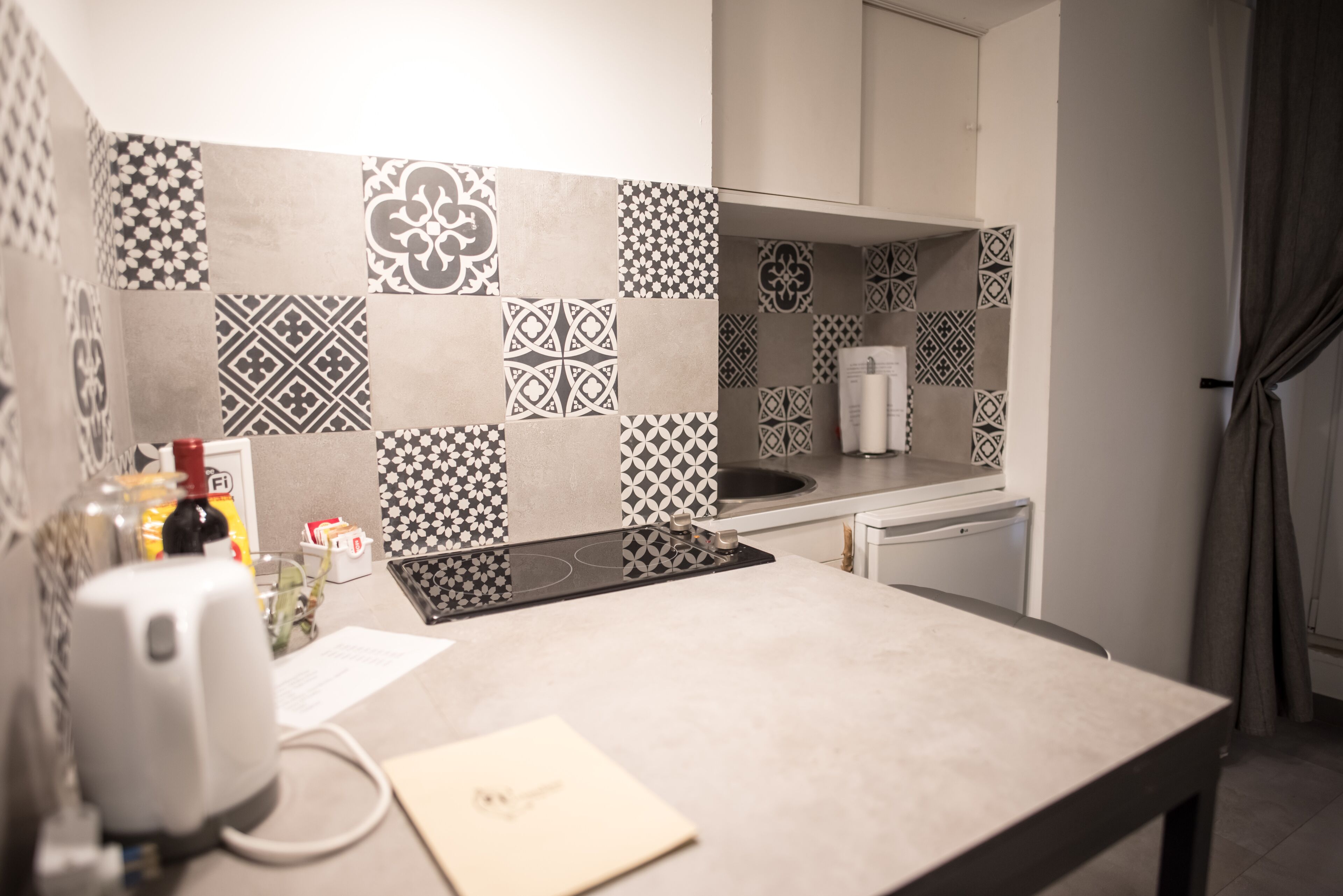 Una cocina con baldosas estampadas, encimera, estufa y lavamanos.