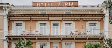A hotel with a balcony, a sign reading 'HOTEL ADRIA,' and a traditional architectural style.