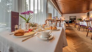 Un coin repas avec une table préparée pour le petit-déjeuner, comprenant des croissants, du café et des fruits.