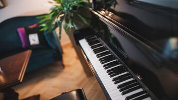 Un piano de cola en una habitación con piso de madera y un sofá verde.
