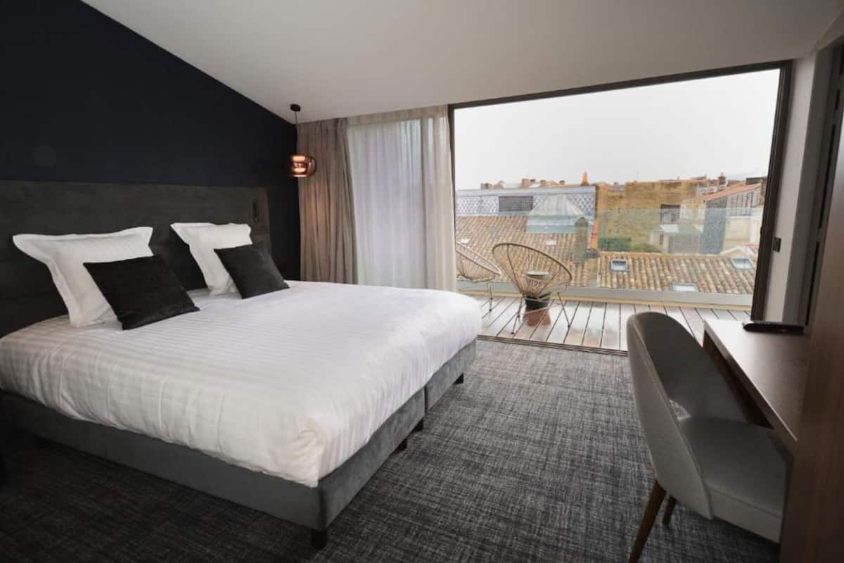 Ein modernes Hotelzimmer mit einem großen Bett, einem Schreibtisch und Blick auf die Stadt.