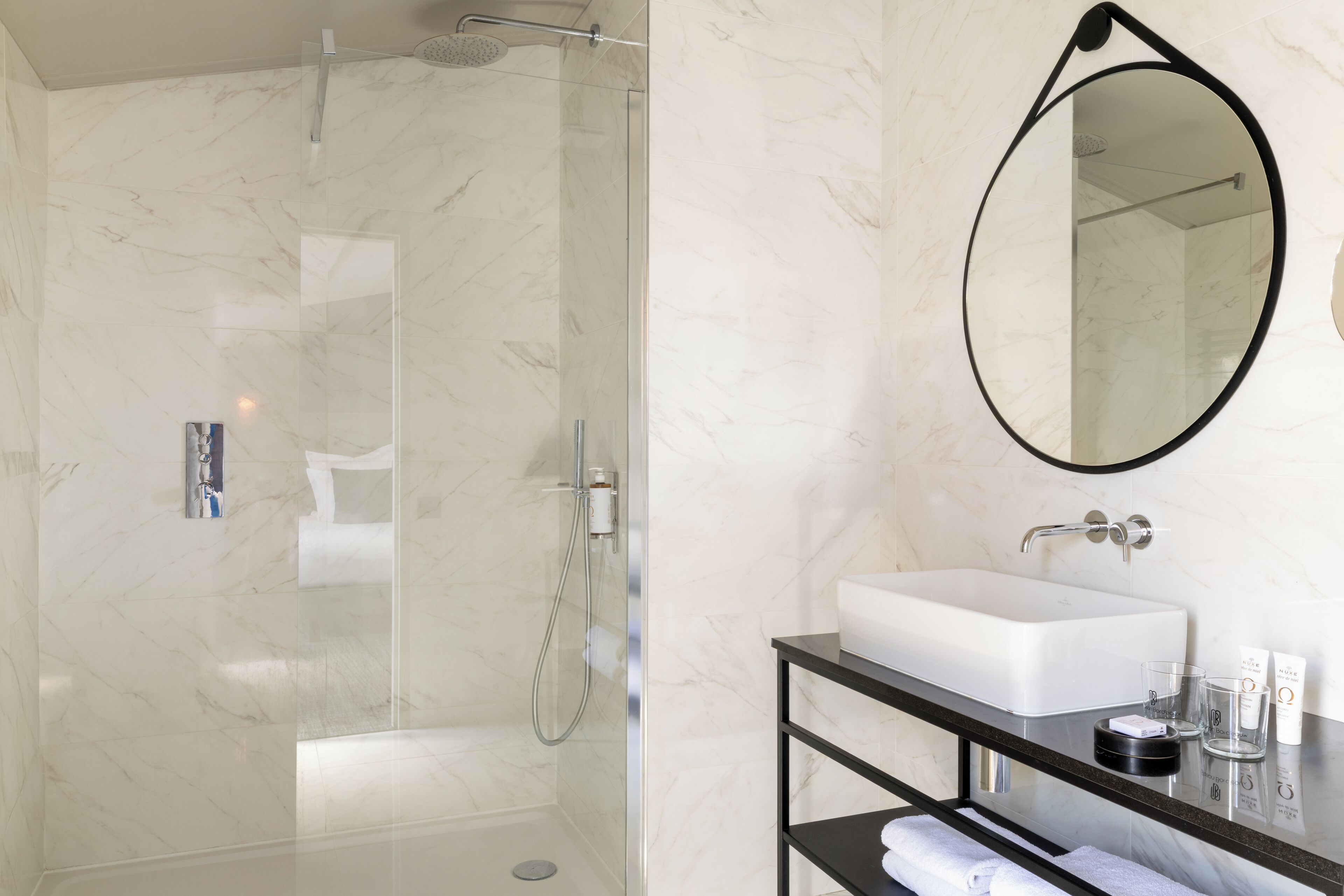 A modern bathroom with a glass-enclosed shower, a white sink, and a black vanity.