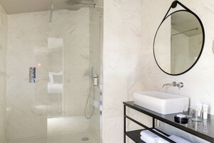 Un baño moderno con cabina de ducha de vidrio, lavabo blanco y tocador negro.