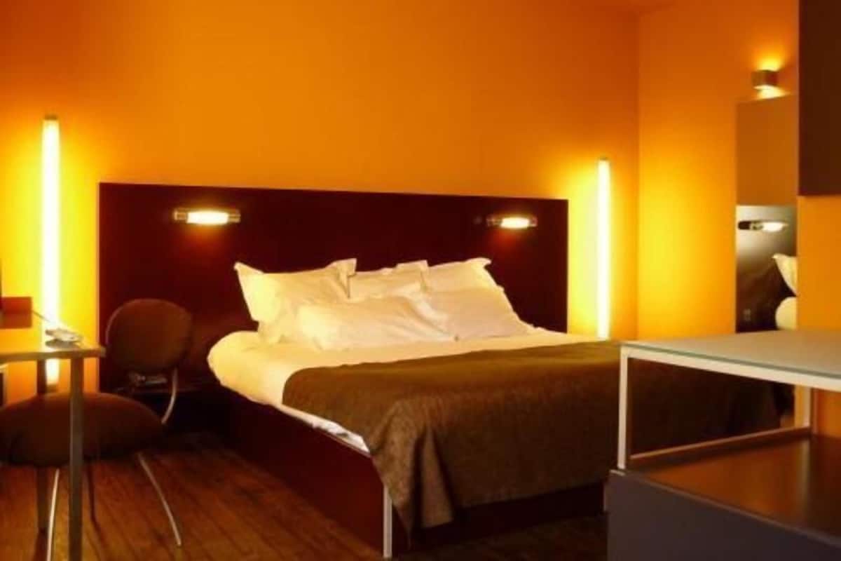 A hotel room with a bed, bedside table, chair, and a nightstand.