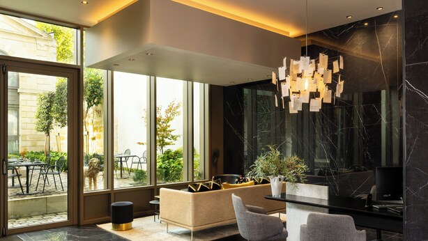 A modern interior with a sofa, two chairs, a desk, and a hanging light fixture. - La Maison Bord'eaux (Bordeaux)
