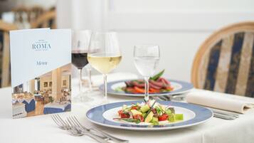 Un tavolo da pranzo imbandito con piatti di cibo, bicchieri di vino e un menu.