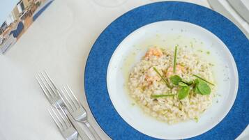 Prato de risoto com camarões e ervas em um prato branco com borda azul.
