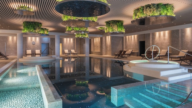 Un área de piscina interior moderna con varias zonas de estar y una fuente central.